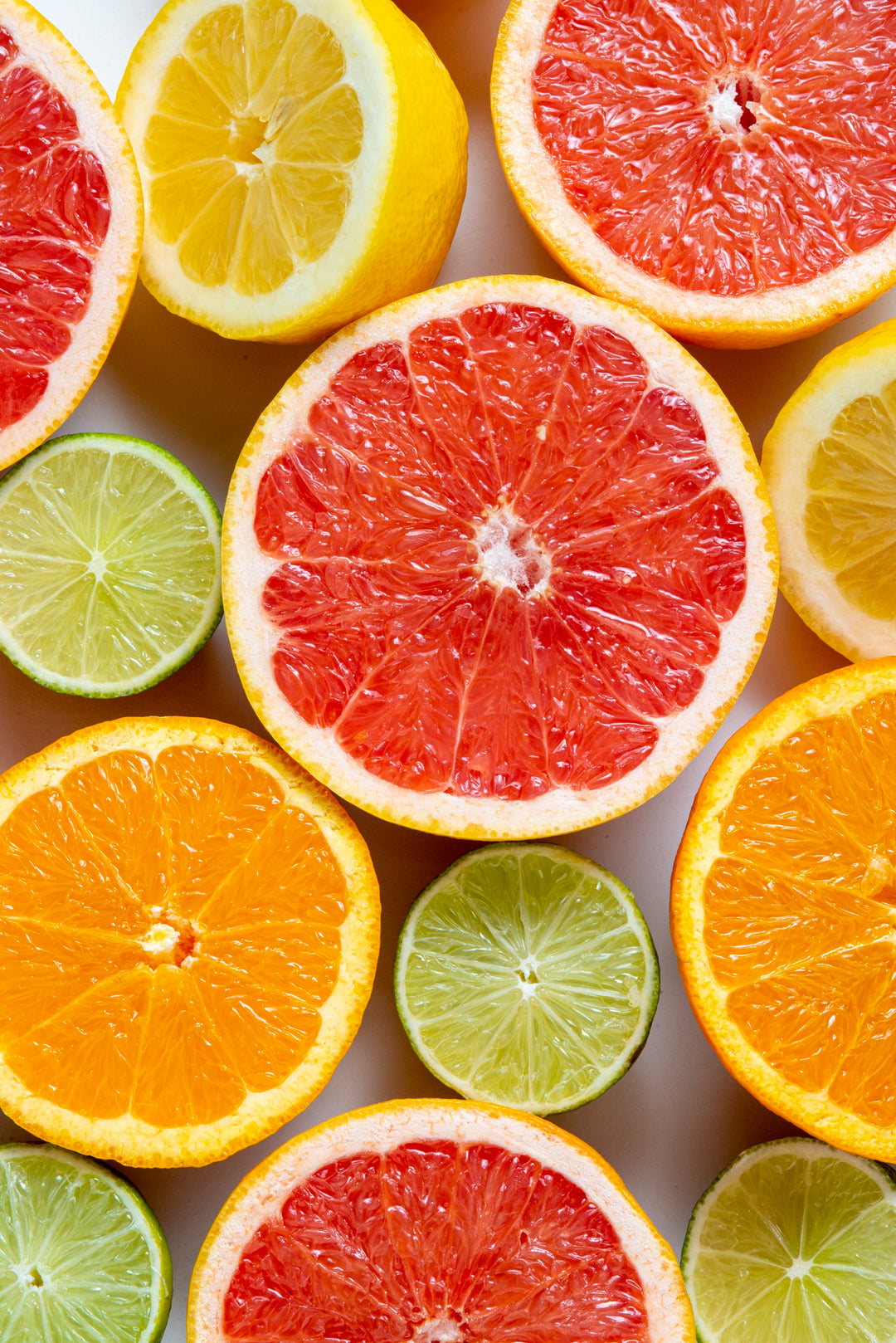 An overhead view of sliced citrus fruits, including grapefruits, oranges, lemons, and limes, displaying vibrant colors and juicy textures.